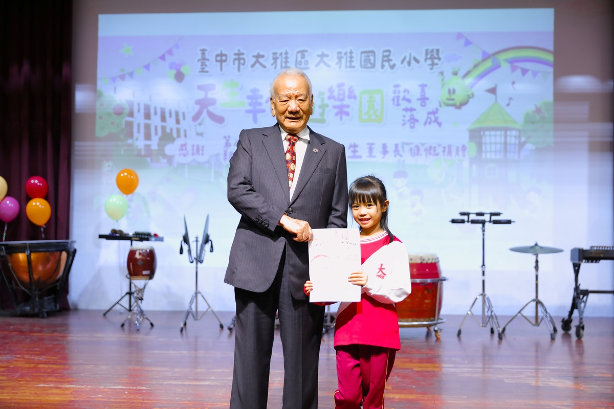 大雅國小學童代表送上感恩卡，謝謝楊天生爺爺(左)送他們一座遊樂園。圖片