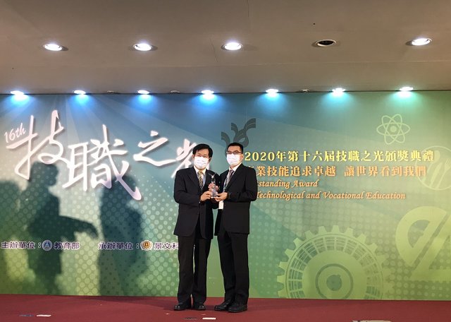 本校視傳系獲獎團隊指導老師林慶利(右)代表接受教育部長潘文忠(左)表揚。
