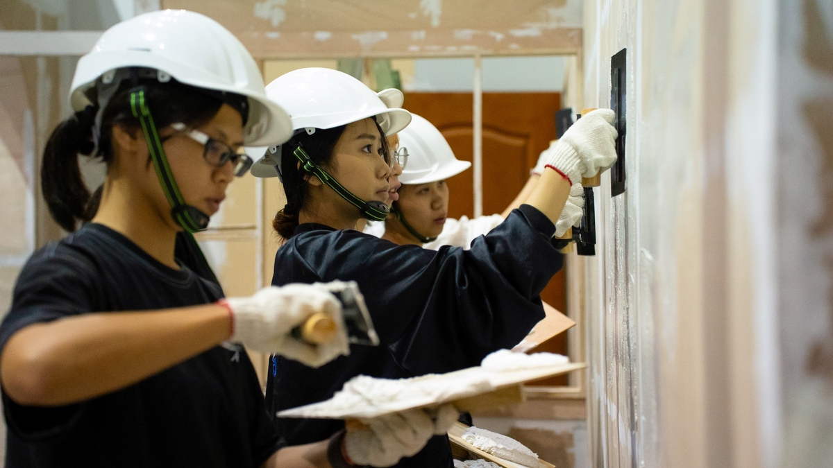 Students learning hands-on skills in set production within a film studio.Image